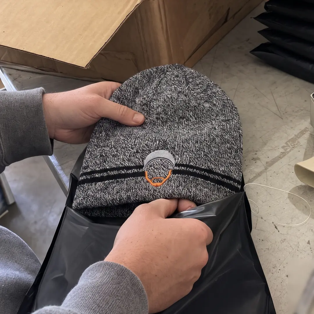 A Guru beanie being packed into a black mailer
