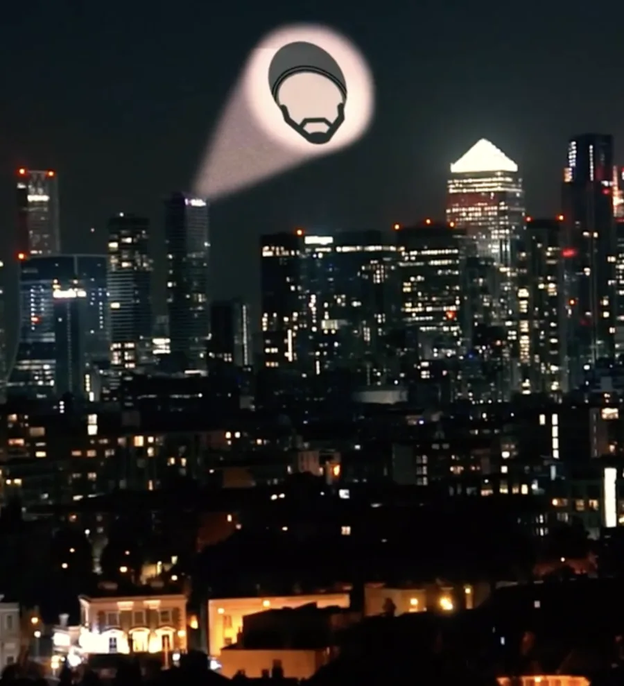 The Guru's beanie logo projected like a bat-signal over the London skyline at night