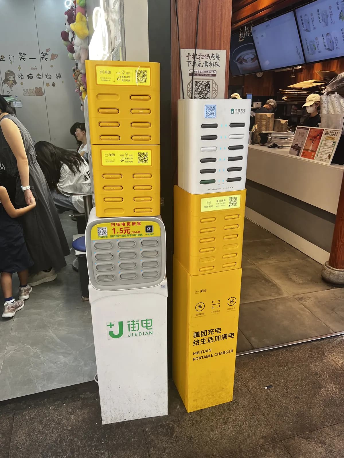 Powerbank rental stations from three Chinese operators lined up inside a restaurant